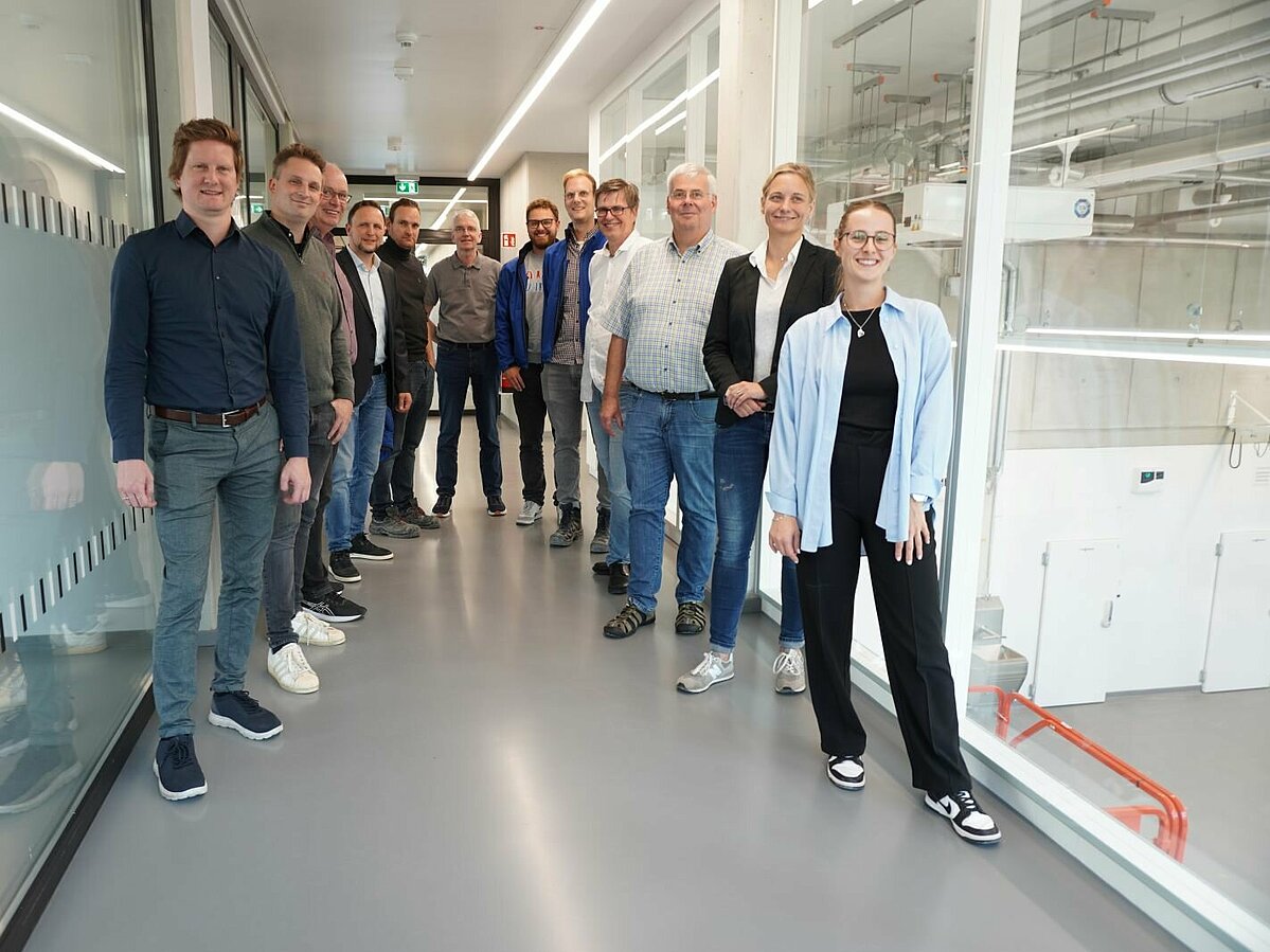 Gruppe von Personen vor Glasscheibe mit Blick in Technikum