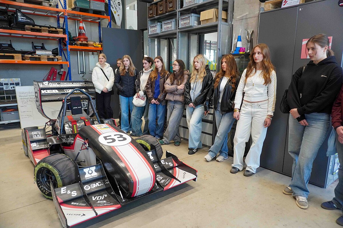 Eine Gruppe von Mädchen steht neben einem Rennauto des Racing Teams der TH OWL