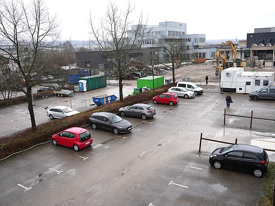 Foto: Parkplatz mit Autos, im Hintergrund reißen Bagger das alte Laborgebäude der TH OWL ab.