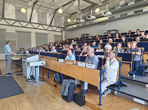 Photo: A group of experts is seated throughout a lecture hall.