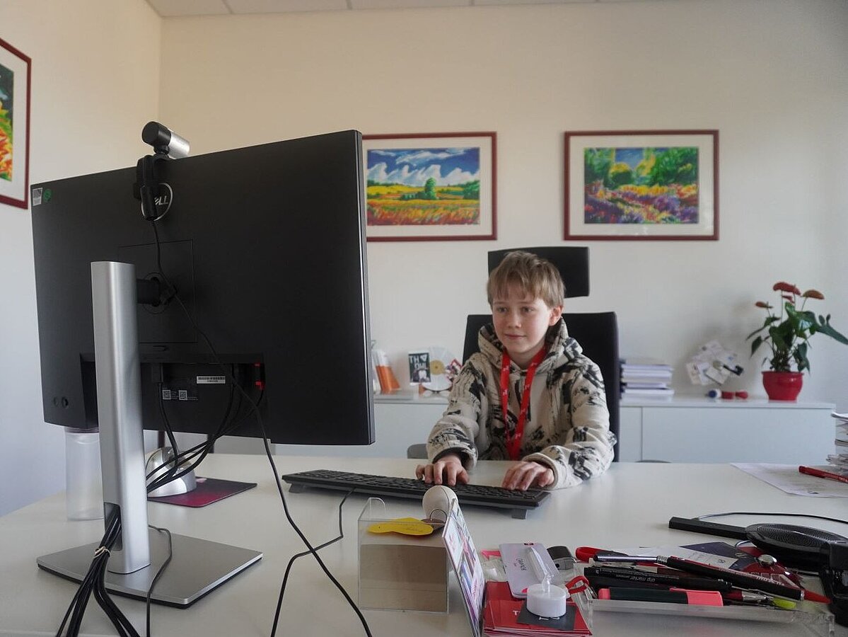 Ein Junge sitzt an einem Schreibtisch und arbeitet am Computer.