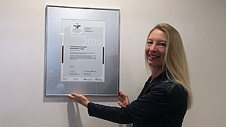 Marianne Langstrof vor einem eingerahmten Zertifikat 