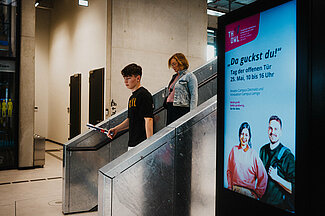 Junge und Frau gehen große silberne Treppe hinunter.