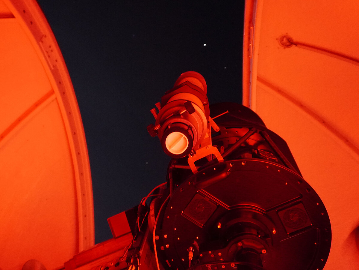 Foto: Ein Teleskop der Sternwarte unter der geöffneten Kuppel. Im Hintergrund der Nachthimmel. 