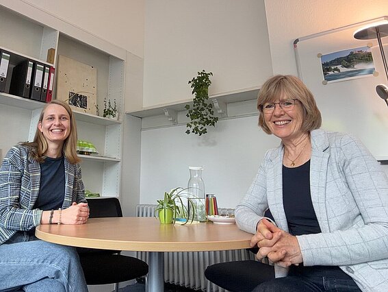 Photo: Two women are sitting at a round table in an office. 