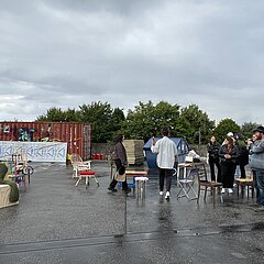 Draußen, ein paar Menschen und ein paar Stühle versammelt