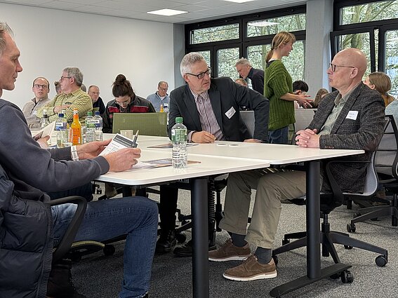 Foto: Mehrere Personen sind einem Seminarraum der TH OWL in Höxter in einen angeregten Austausch vertieft. Die Atmosphäre ist freundlich. 