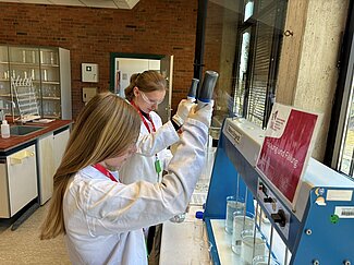 Zwei Mädchen nutzen ein Gerät, um das Wasser zu säubern. 