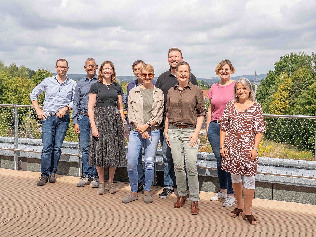 Foto: Neun Personen, davon vier Männer, stehen auf einer Terrasse des InnovationSPIN in Lemgo.