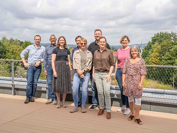 Foto: Neun Personen, davon vier Männer, stehen auf einer Terrasse des InnovationSPIN in Lemgo.