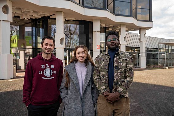 Drei Studierende des Studiengangs General Engineering stehen vor einem Hochschulgebäude auf dem Campus der TH OWL. Sie kommen aus Griechenland, Deutschland und der Demokratischen Republik Kongo und studieren gemeinsam in dem internationalen, zweisprachigen Ingenieurstudiengang.