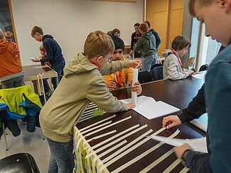 Eine Gruppe von Jungen baut Türme aus Papier und Kreppband.