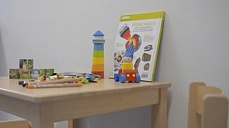 Ein Tisch im Eltern-Kind-Raum, auf dem buntes Spielzeug drapiert ist.