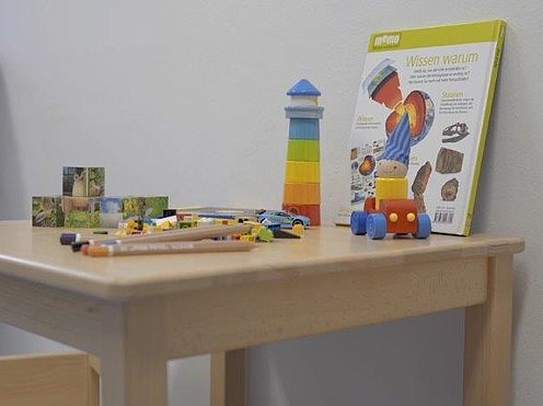 Ein Tisch im Eltern-Kind-Raum, auf dem buntes Spielzeug drapiert ist.