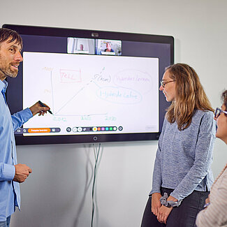Beratungsangebote Dozent erläutert zwei weiteren Personen Inhalte an einem digitalen Whiteboard.