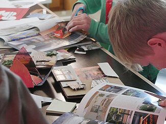 Mehrere Jungen suchen Bilder in Zeitschriften heraus und scheiden diese anschließend aus. 