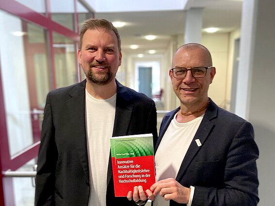 Christian Einsiedel (links) und Dr. Christoph Harrach präsentieren den Sammelband "Innovative Ansätze für die Nachhaltigkeitslehre und Forschung in der Hochschulbildung".