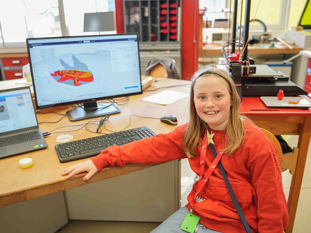 Ein Mädchen zeigt stolz das Motiv, das sie sich für den 3D-Drucker ausgesucht hat. Das Motiv ist ein Drache.