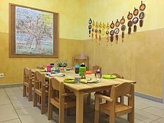 Essensbereich der Kita Paulinchen Gelb gestrichener Essensbereich der Kita Paulinchen mit einem langen, bunt eingedeckten Tisch und Kinderstühlen aus Holz