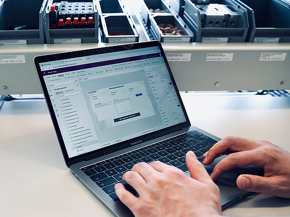 Ein Laptop auf einem Schreibtisch wird von zwei Händen bedient