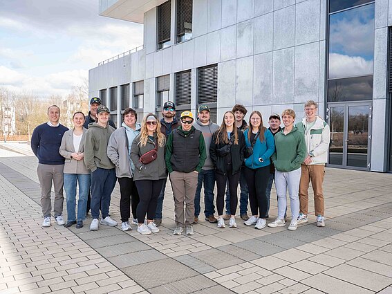 [Translate to Englisch:] Foto: Eine Gruppe Menschen steht vor einem Gebäude und posiert für ein Gruppenfoto.