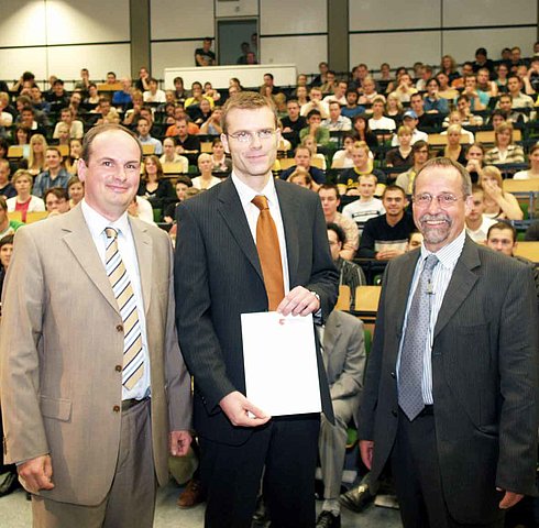 Grafik: Rektor Prof. Tilmann Fischer (r.) überreicht die "Go Global"-Urkunde an Christoph Wenderdel (M.), Laudator Dr. Thomas Lüttenberg (l.) gratuliert.