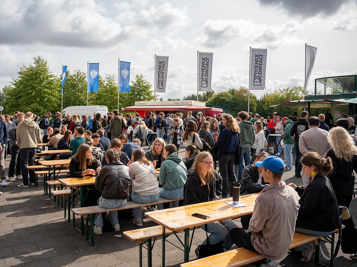 [Translate to Englisch:] Vor der Arena luden Food-Trucks zum Verweilen und zum Kennenlernen ein. Die Studierenden genossen das schöne Wetter. 