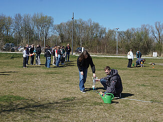 Ein Mann hilft einem Jungen den Start für die Wasserrakete vorzubereiten.