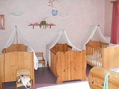 Schlafraum der Kita Sterntaler mit hölzernen Kinderbetten und jeweils weißen Stoffhimmeln darüber 