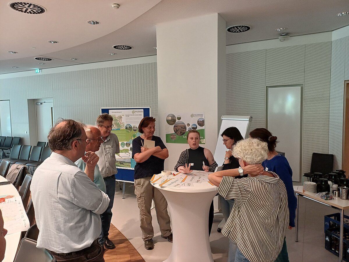 Tagungsteilnehmer:innen diskutierend an einem Stehtisch.