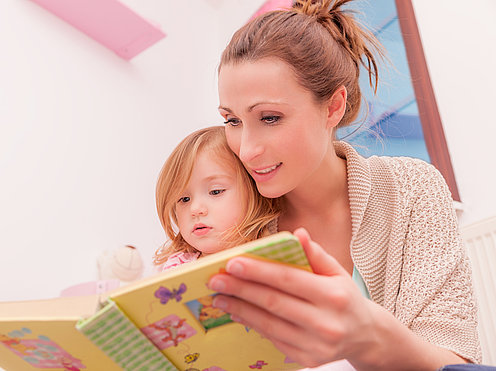 Frau mit Kind auf dem Schoß beim Vorlesen