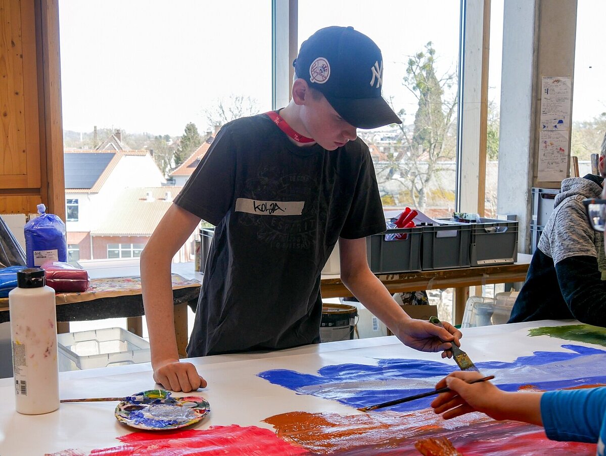 Zwei Jungen malen gemeinsam ein großes Kunstwerk.
