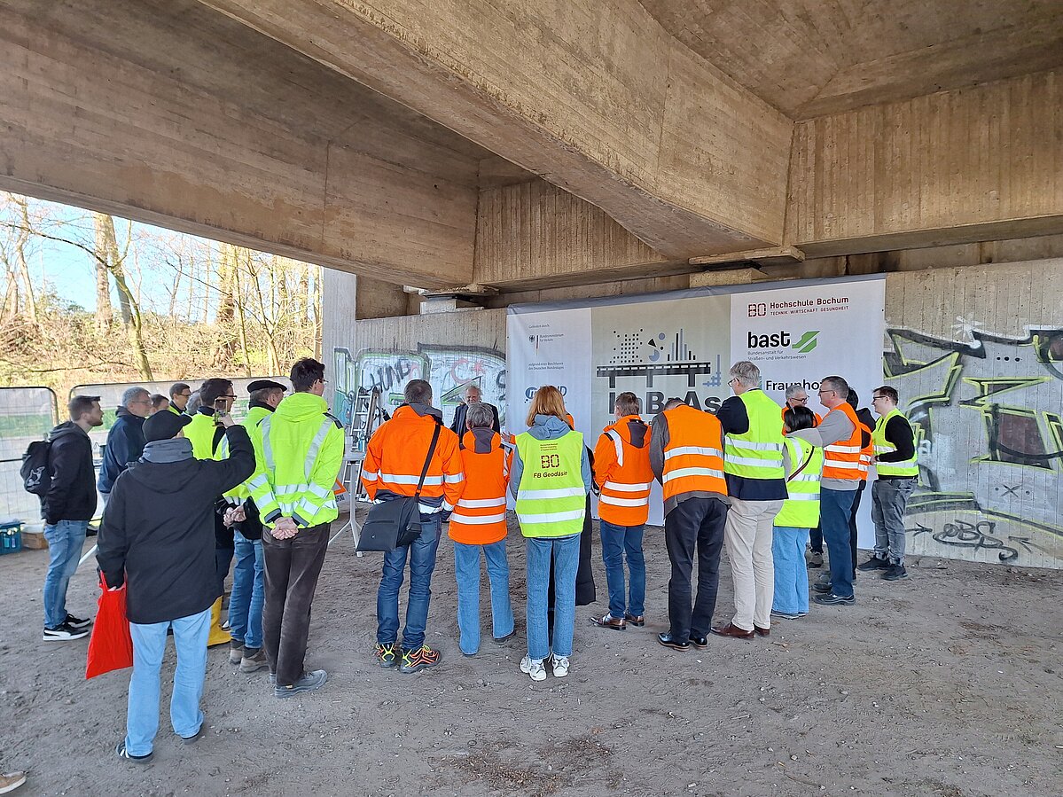  Gruppe von Menschen von hinten zu sehen. Hören unter einer Betonbrücke der Begrüßung zu.