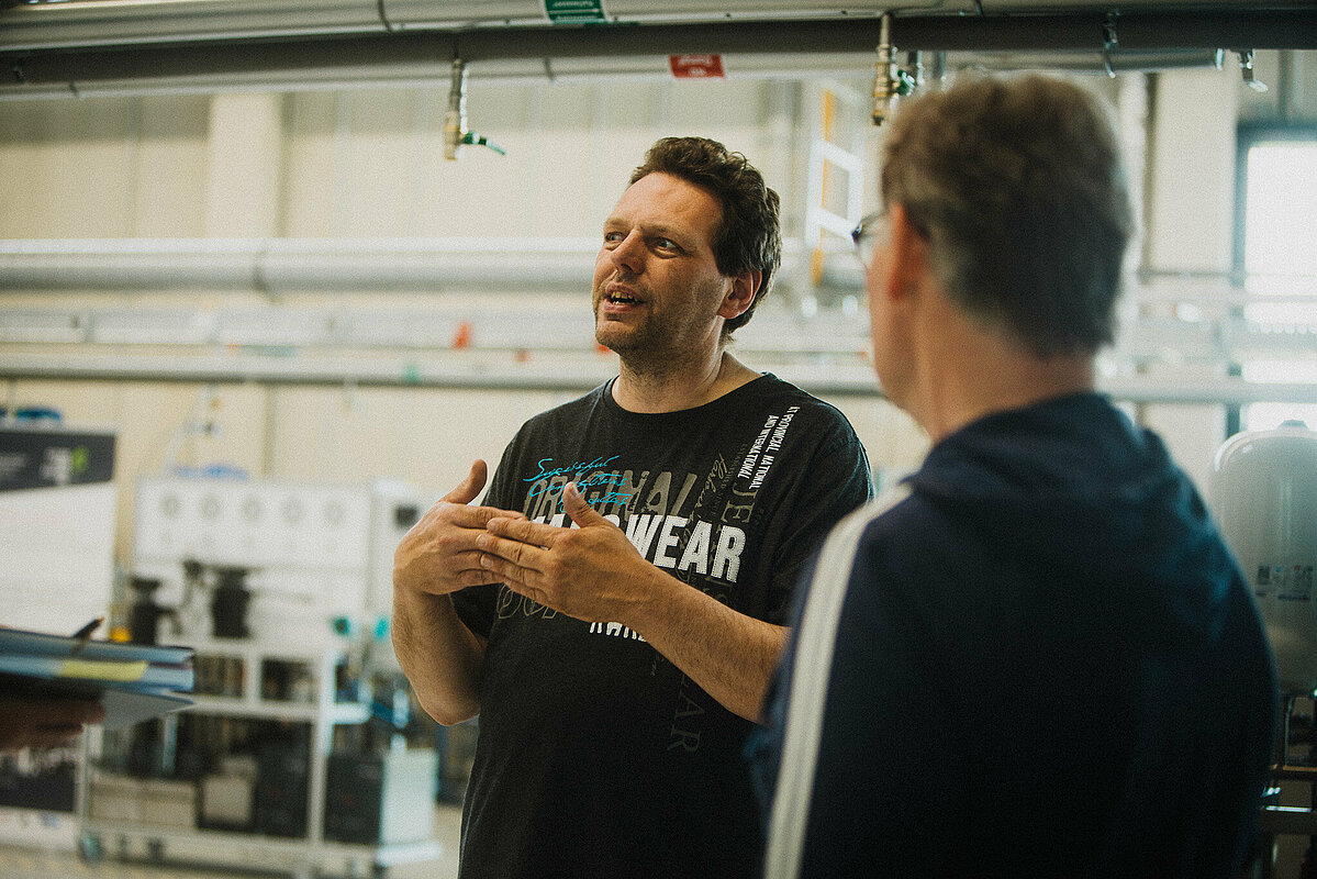 Zwei Männer unterhalten sich in Laborhalle.
