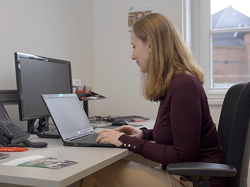 Frau sitzt am Schreibtisch und arbeitet am Laptop Frau sitzt am Schreibtisch und arbeitet am Laptop