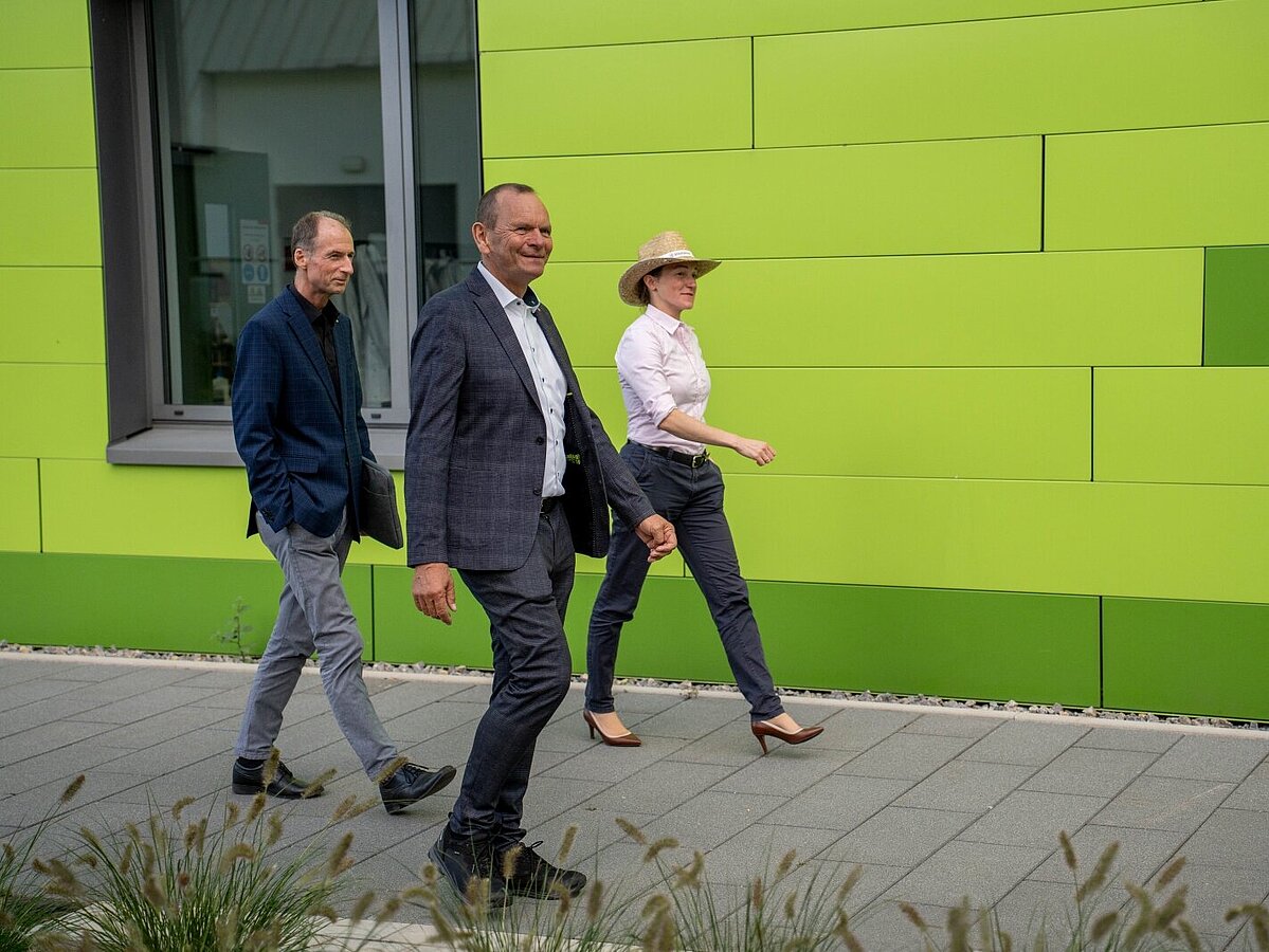 Two men and a woman are walking across the Innovation Campus in Lemgo.