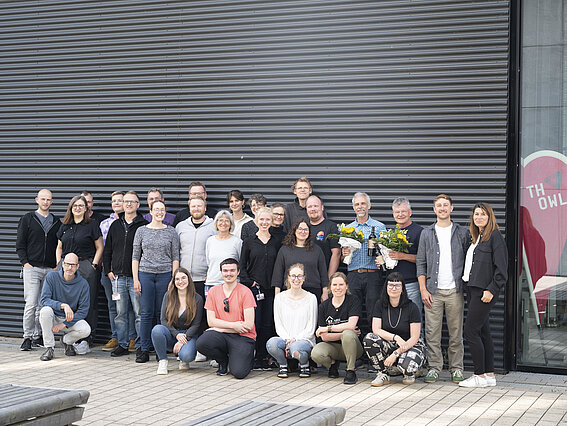 Foto: Das Team des Instituts ILT.NRW blickt in die Kamera. Im Hintergrund steht die Future Food Factory auf dem Innovation Campus Lemgo.