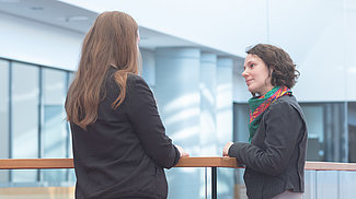 Gesprächssituation zwischen zwei Frauen, die einander zugewandt an einem Geländer stehen Gesprächssituation zwischen zwei Frauen, die einander zugewandt an einem Geländer stehen