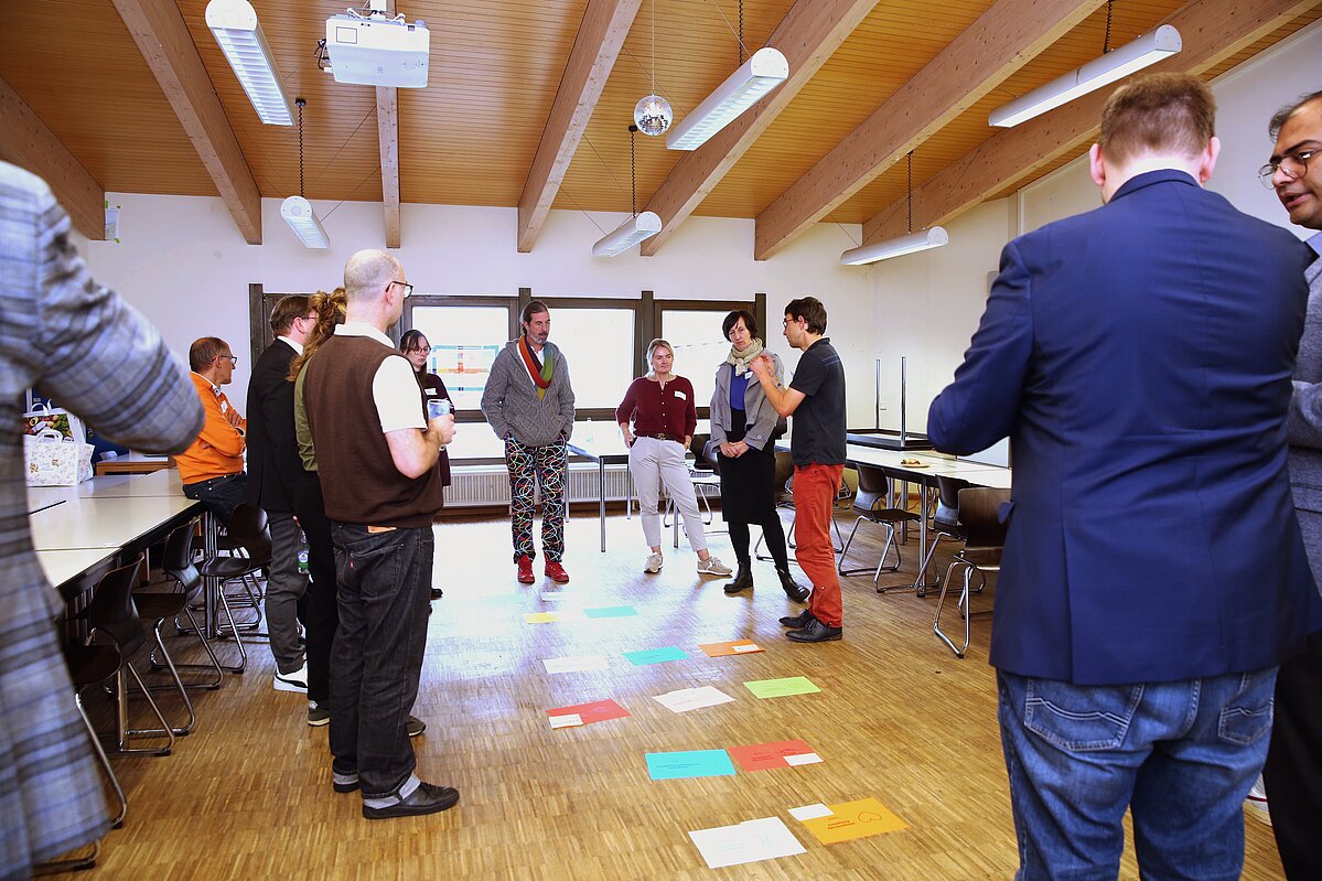 Spiral-Curriculare Mittagspause: Dr. Martin Gerner (rote Hose) leitet eine Aufstellungsarbeit zu Nachhaltigkeits-Kompetenzen im Raum an. Foto: THWS/Patrick Daratha