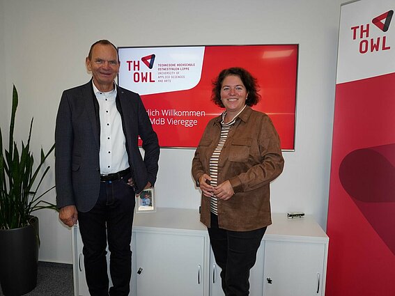 Frau und Mann vor einem Bildschirm mit TH OWL Logo in einem Büro.