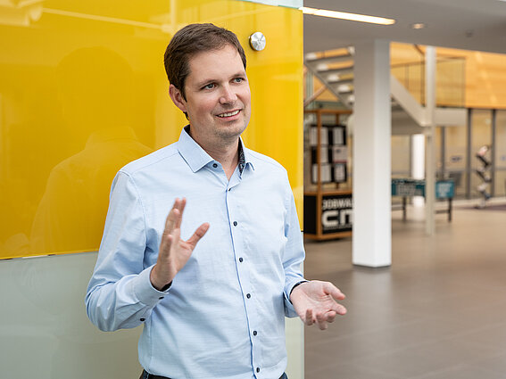 Photo: A man is standing in the lobby of an office building in front of a yellow wall. 