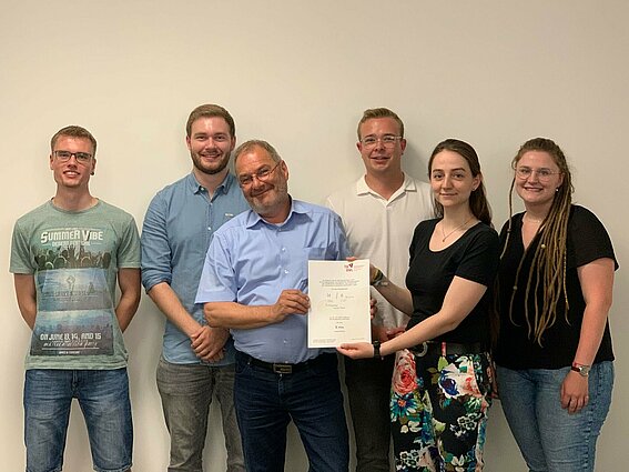 Gruppe Studierender mit Professor und Auszeichnung.