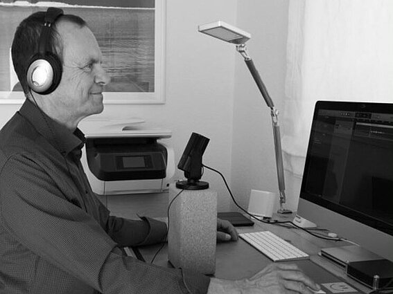 Präsident Prof. Dr. Jürgen Krahl sitzt vor einem Mikrofon und einem Bildschirm und spricht in die Technik bei der Aufnahme des TH OWL Podcasts.