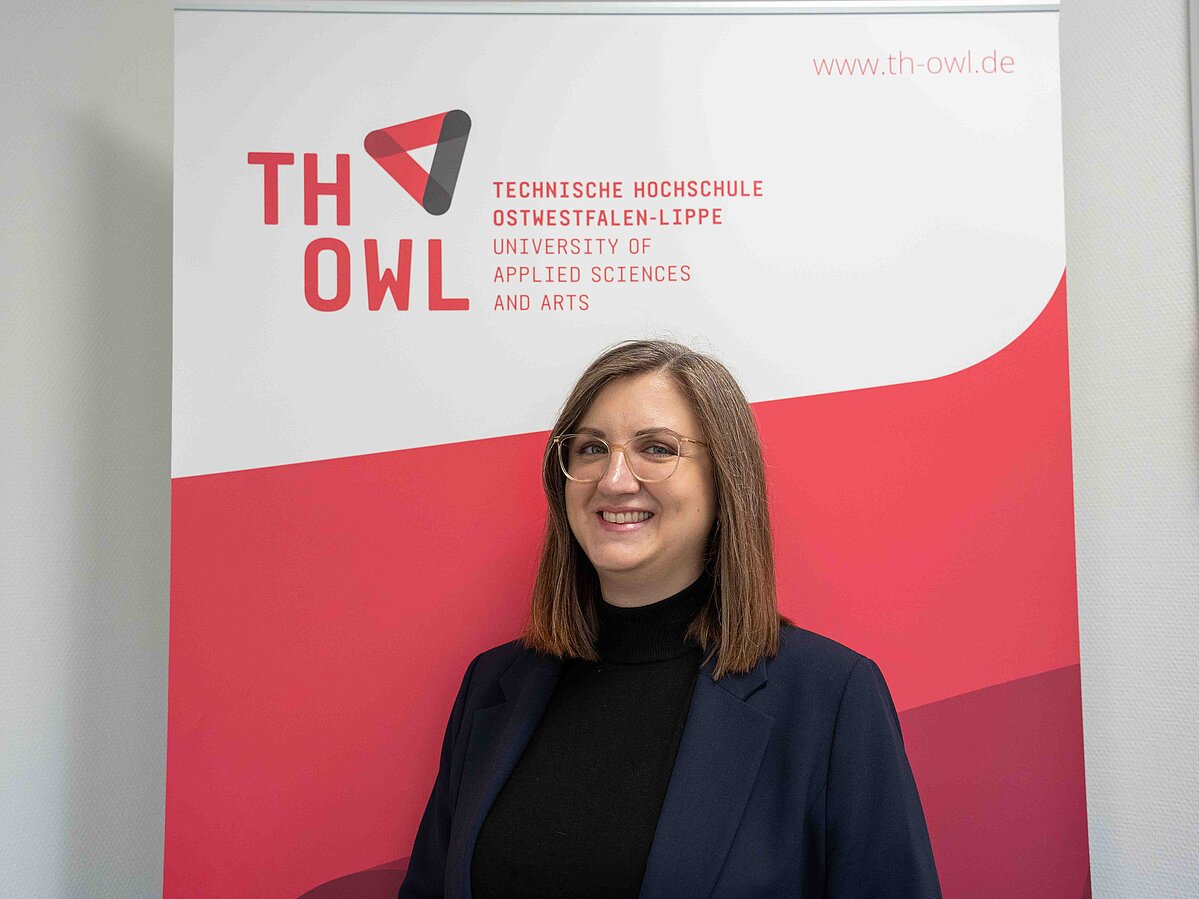 Foto: Eine Frau steht vor einem TH OWL Roll-Up.