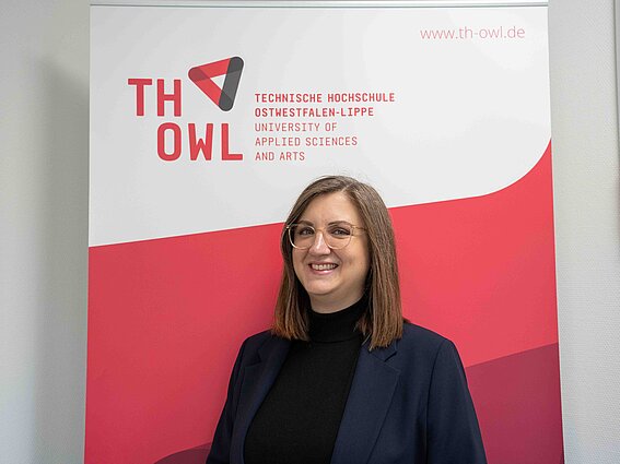 Foto: Eine Frau steht vor einem TH OWL Roll-Up.