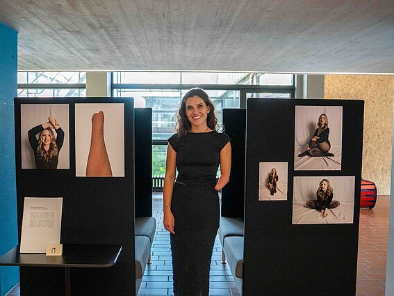Eine Künstlerin steht vor Bildern ihrer Ausstellung. 