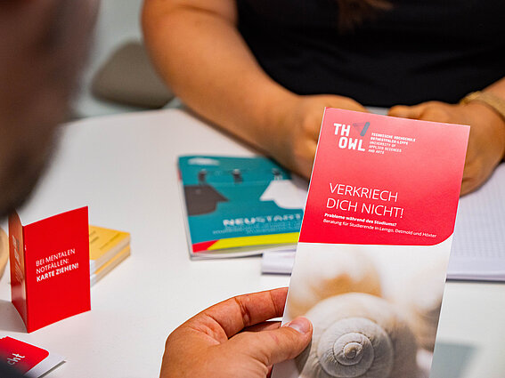 Perspektiven erkennen oder entwickeln: Online-Themenreihe unterstützt Studierende Foto: Zwei Personen an einem Tisch. Nur Arme und Hände sind zu sehen sowie Infomaterialien.
