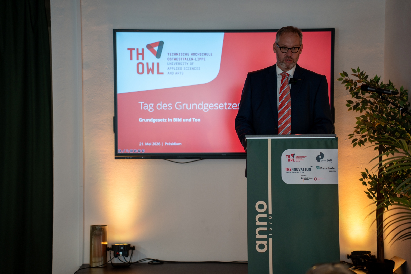 Professor Dr. Florian Hobbeling hält beim „Tag des Grundgesetzes 2026“ der TH OWL einen Vortrag am Rednerpult. Im Hintergrund ist die Präsentation zur Veranstaltung zu sehen.