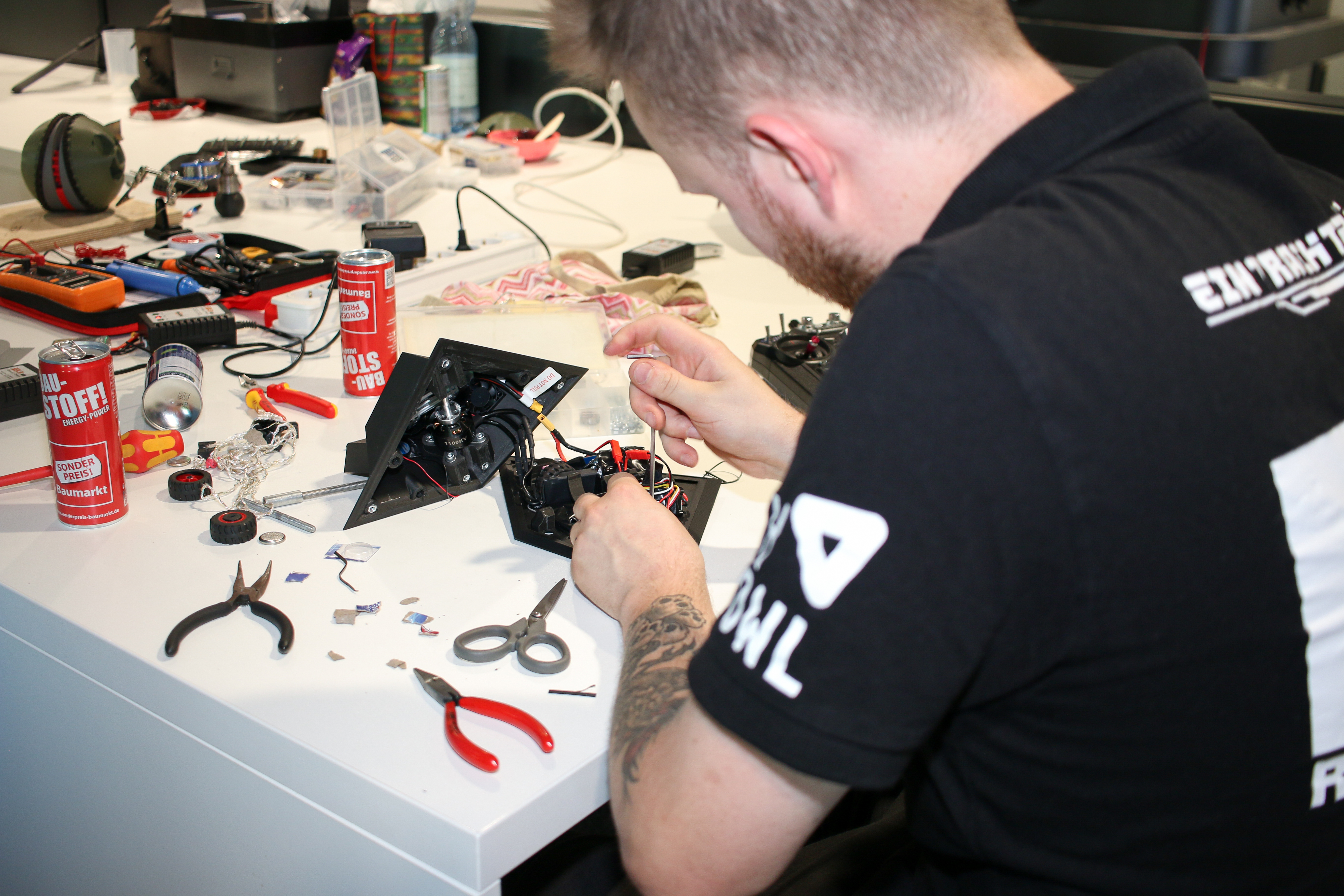 A student is sitting at a table, repairing a robot. 