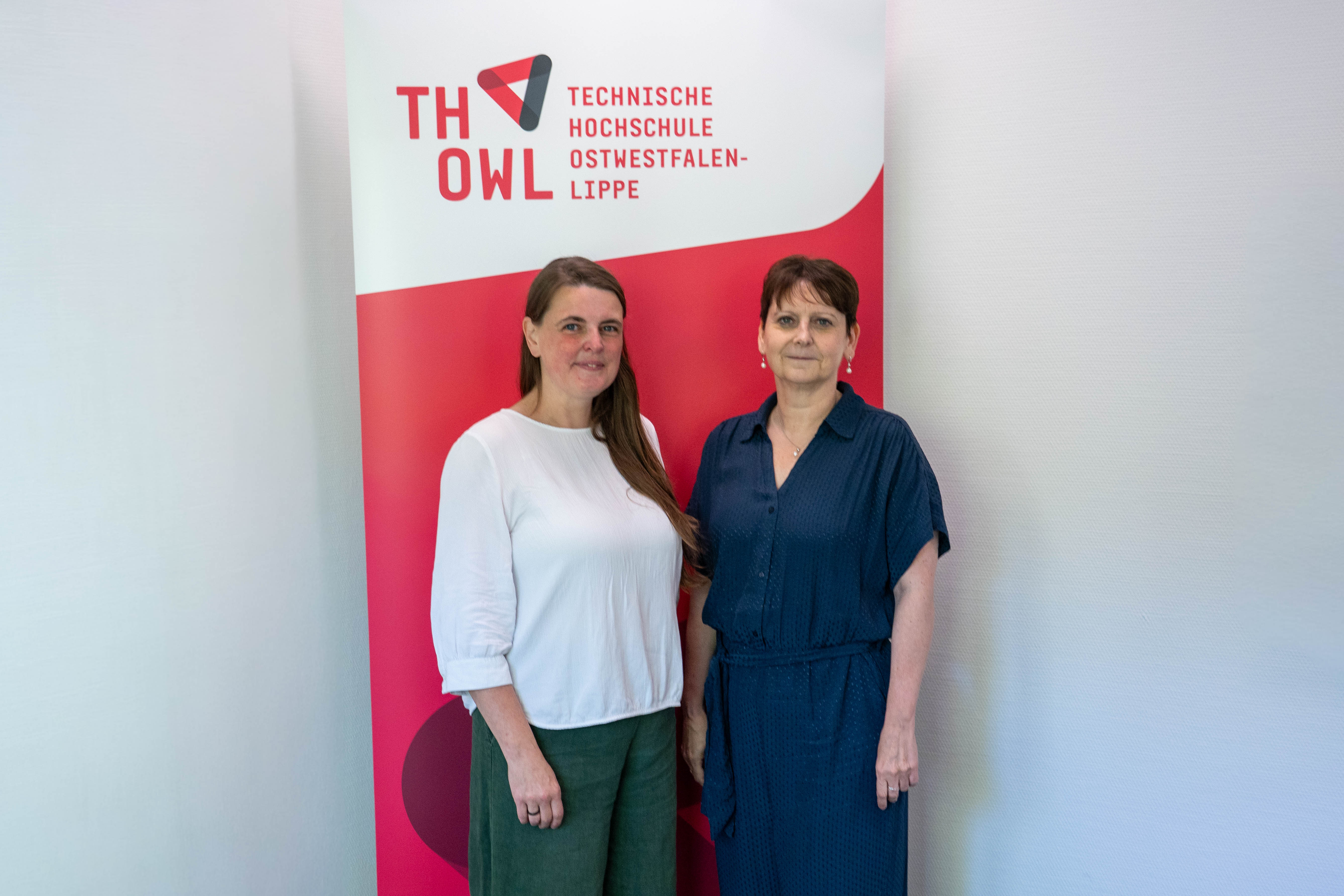 Foto: Zwei Frauen stehen vor einem Roll-up-Display der TH OWL. 
